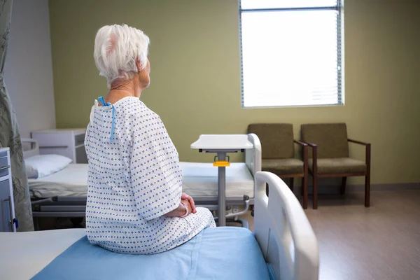 Vue arrière d'une patiente âgée réfléchie assise sur son lit — Photo