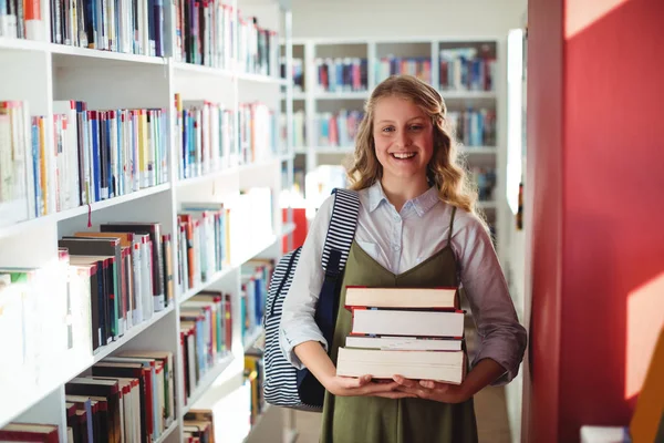 Scolaretta in piedi con pila di libri — Foto Stock