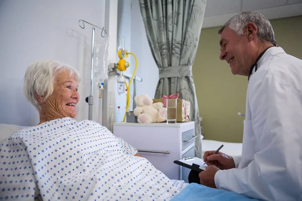 Arzt diskutiert Arztbericht mit Seniorin — Stockfoto