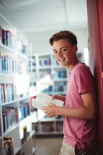 Estudante segurando livro na biblioteca — Fotografia de Stock