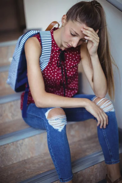 Sad schoolgirl sitting alone on staircase — Stock Photo, Image