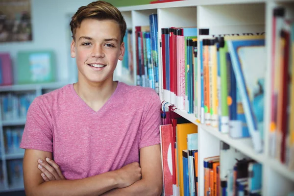 Estudante de pé com os braços cruzados na biblioteca — Fotografia de Stock