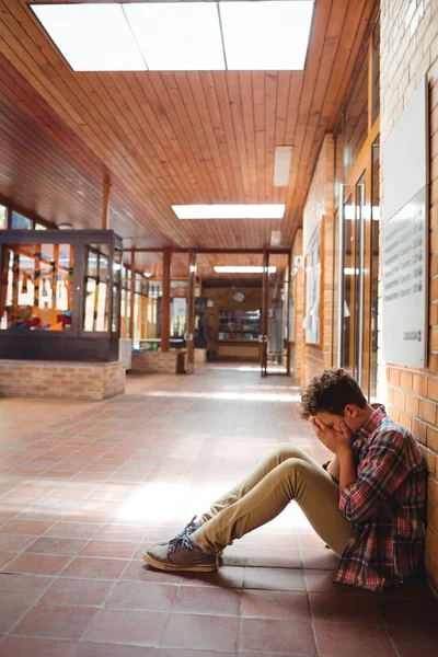 Sorgliga skolpojke sitter ensam i korridoren — Stockfoto