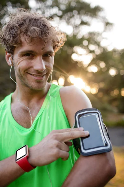 Smiling jogger listening to music from phone — Stock Photo, Image
