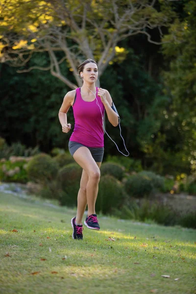 Corredor feminino ouvindo música enquanto jogging — Fotografia de Stock