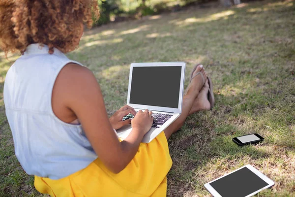 Mujer sentada en el parque y usando el ordenador portátil — Foto de Stock
