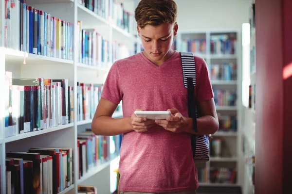Schoolboy usando tablet digital na biblioteca — Fotografia de Stock