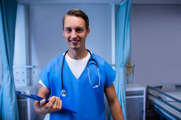 Male doctor standing with clipboard — Stock Photo, Image