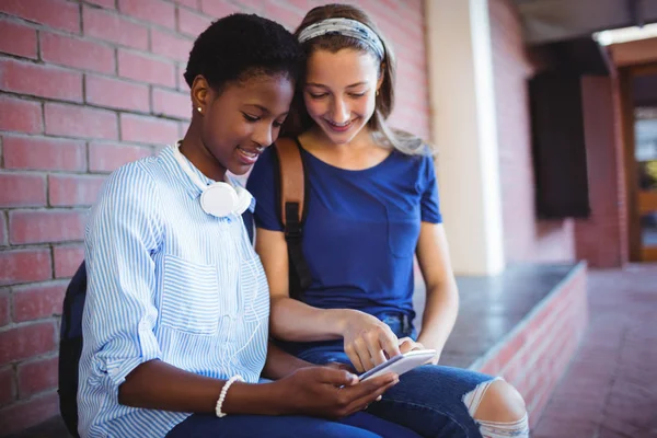 Schoolmeisjes zitten tegen de muur — Stockfoto