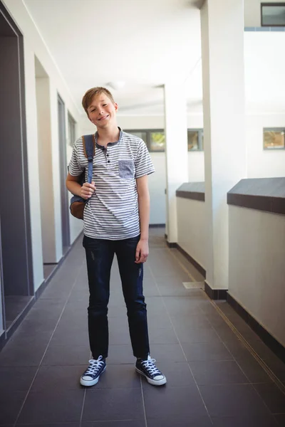 Школьник, стоящий со школьной сумкой в коридоре — стоковое фото