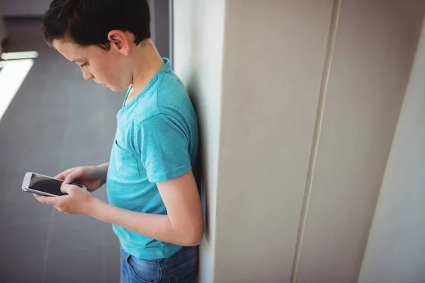 Schoolboy usando telefone celular no corredor — Fotografia de Stock