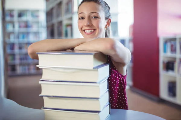 Schoolmeisje scheve van gestapelde boeken — Stockfoto