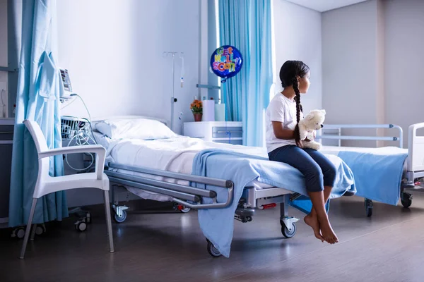 Patient sitting on bed with teddy bear — Stock Photo, Image