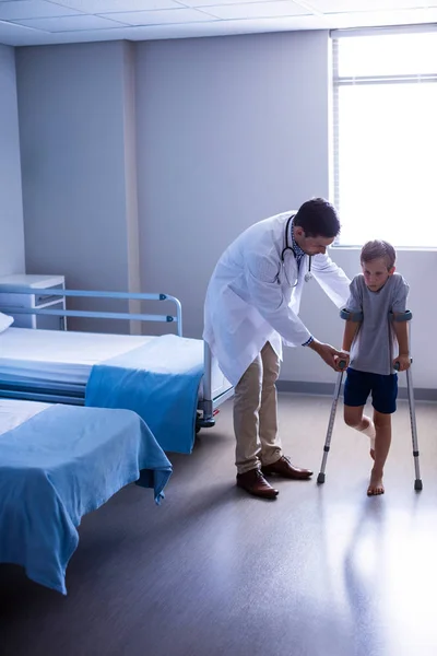 Arts helpen gewonde jongen te lopen met krukken — Stockfoto