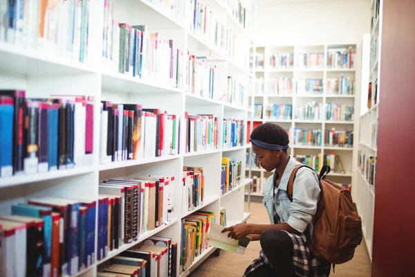 Schülerin wählt Buch aus Bücherregal — Stockfoto