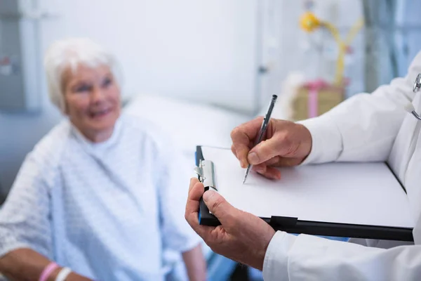 Médico discutindo relatório médico com paciente sênior — Fotografia de Stock