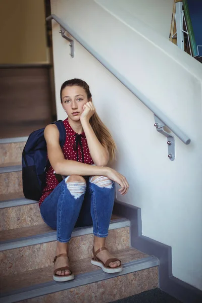 Sad schoolgirl sitting alone on staircase — Stock Photo, Image