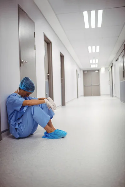 Θλιβερή χειρουργός κάθεται στο πάτωμα στον διάδρομο — Φωτογραφία Αρχείου