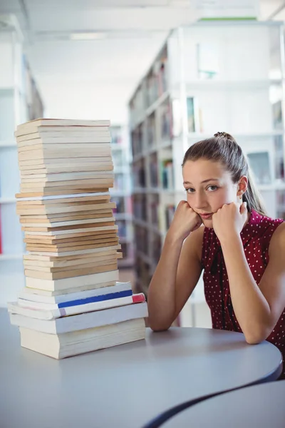 Smutný školačka při pohledu na stoh knih — Stock fotografie