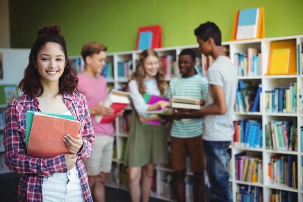 Estudante segurando livro na biblioteca — Fotografia de Stock