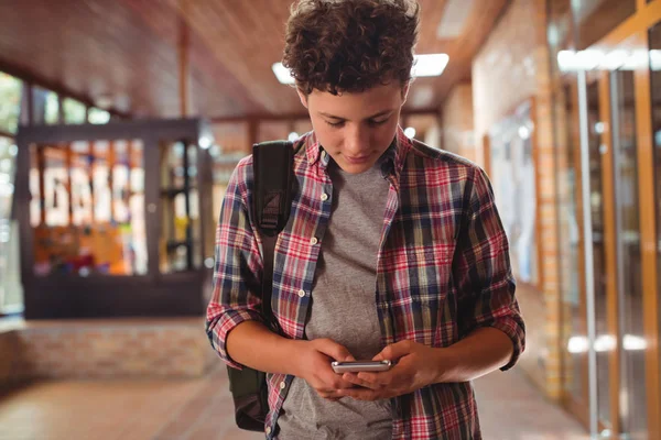 Školák, používající mobilní telefon v chodbě — Stock fotografie