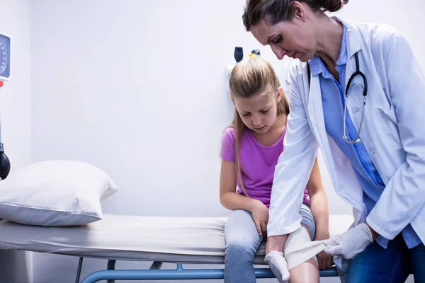 Médico poniendo vendaje en pierna lesionada del paciente —  Fotos de Stock