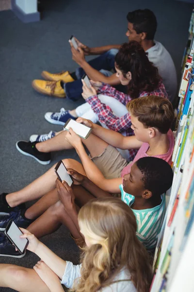 Studenci przy użyciu telefonu komórkowego w bibliotece — Zdjęcie stockowe