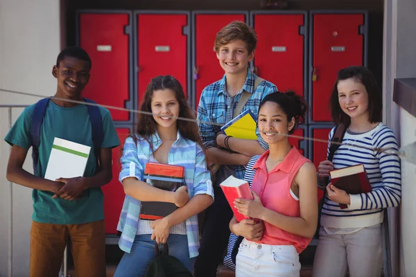 Студенти, які тримають книги, що стоять у шкільному кампусі — стокове фото