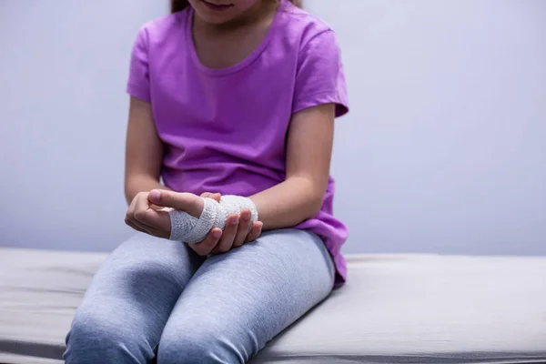 Дівчина з травмованою рукою сидить на ліжку — стокове фото