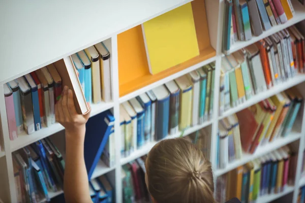 Школярка вибирає книгу з книжкової полиці — стокове фото