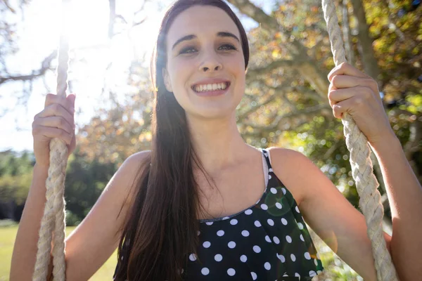 Woman sitting on swing in park — Stock Photo, Image