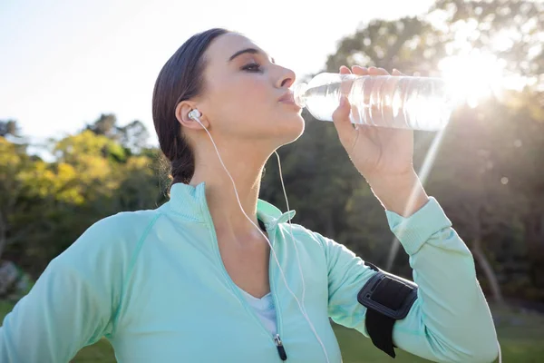 Kvinnliga joggaren dricksvatten i park — Stockfoto