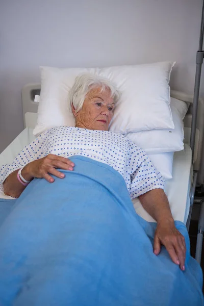 Задумчивый пожилой пациент лежит на кровати — стоковое фото