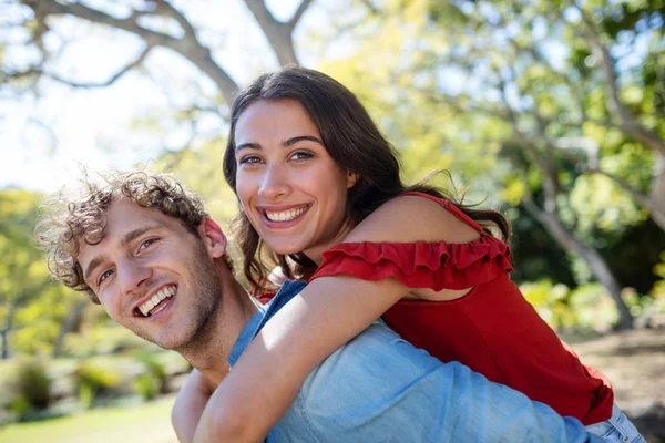 Man giving a piggyback ride to woman — Stock Photo, Image