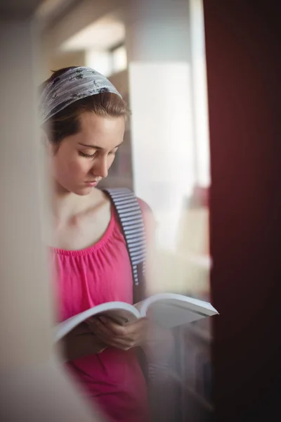 Uczennica uważne czytanie książki w bibliotece — Zdjęcie stockowe