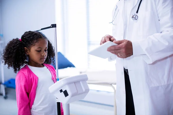 Médico usando tableta mientras mide la altura de la niña —  Fotos de Stock