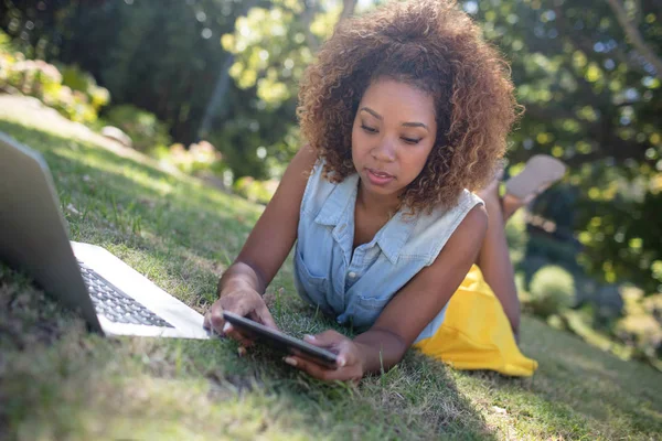 Çim üzerinde yalan ve tablet kullanarak kadın — Stok fotoğraf