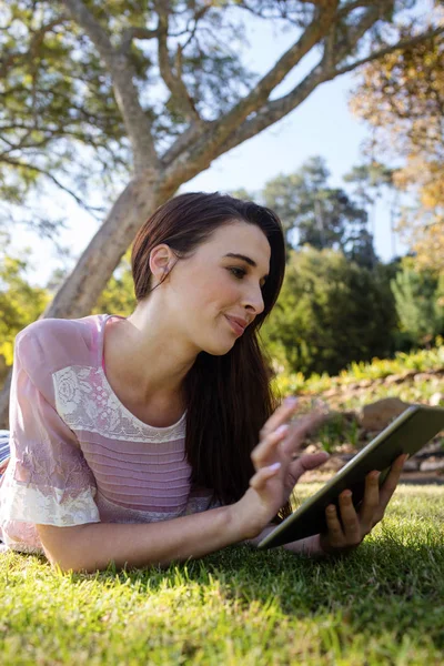 Frau liegt auf Gras und nutzt digitales Tablet — Stockfoto