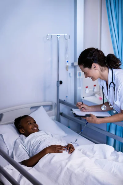 Médico escrevendo na área de transferência enquanto interage — Fotografia de Stock