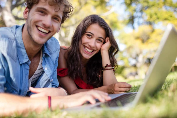 Couple couché sur l'herbe et en utilisant un ordinateur portable — Photo