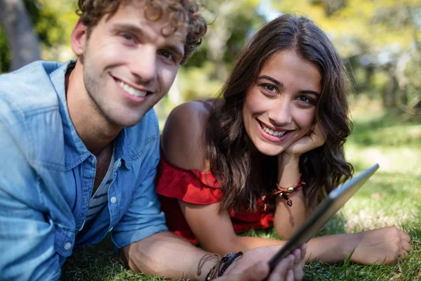 Pareja acostada sobre hierba y usando tableta —  Fotos de Stock