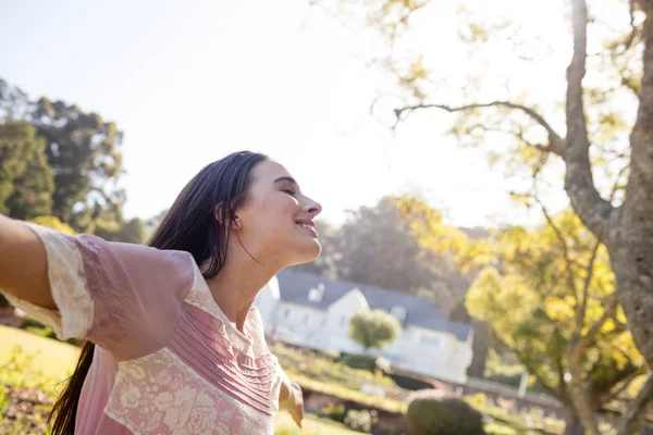 Woman standing with arms outstretched in park — Stock Photo, Image