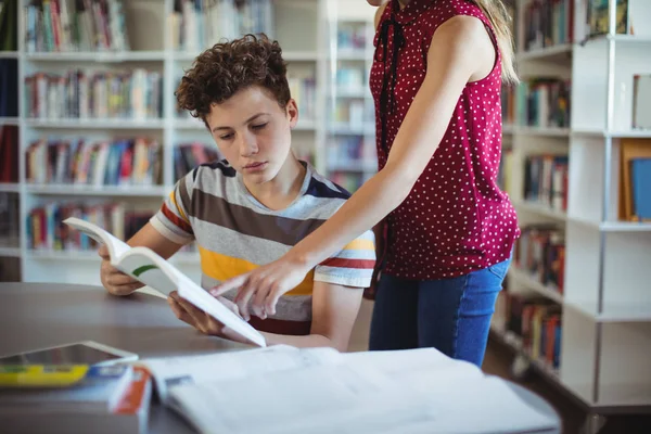 Camarades de classe lisant un livre à la bibliothèque — Photo