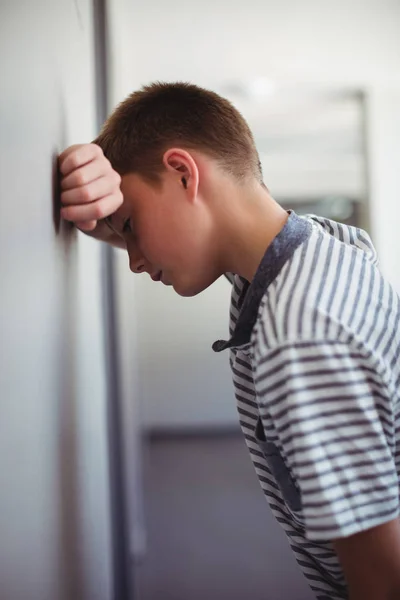 Sad schoolboy leaning head against wall — Stock Photo, Image