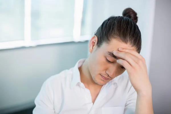 Business executive sitting with hand on forehead — Stock Photo, Image