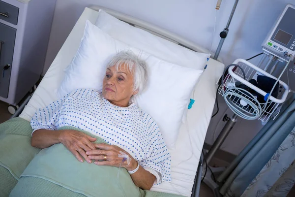 Przemyślane starszy pacjent leży na łóżku — Zdjęcie stockowe