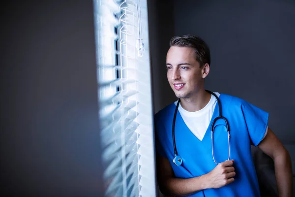 Düşünceli doktor pencereden bakıyor — Stok fotoğraf