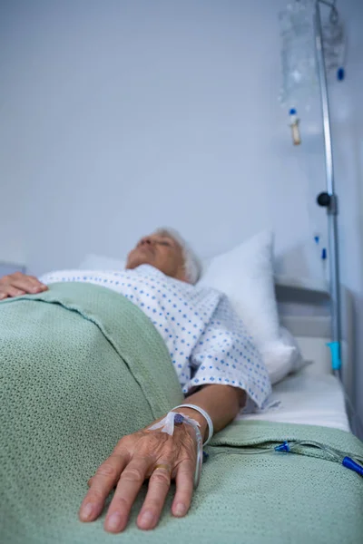 Senior patient hand with saline on bed — Stock Photo, Image