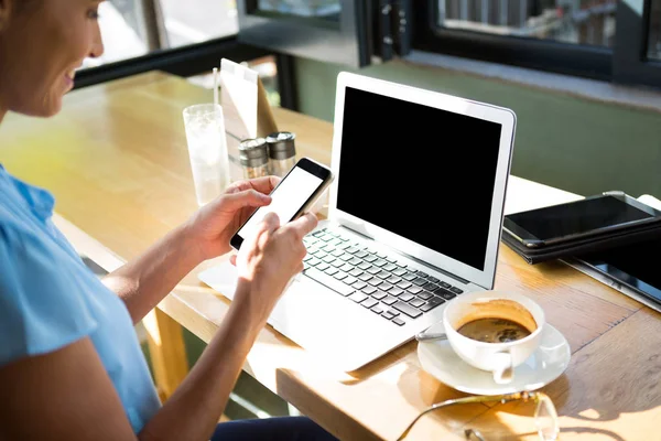 Ejecutiva femenina usando teléfono móvil en cafetería —  Fotos de Stock