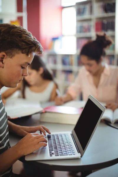 Estudante atento usando laptop na biblioteca — Fotografia de Stock